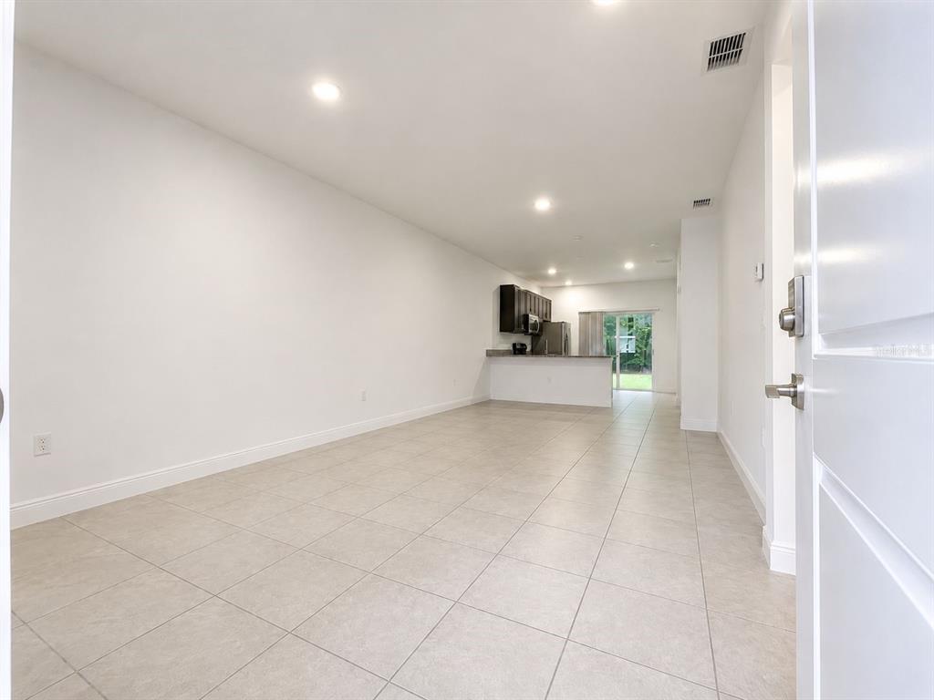 An open-concept living area with light tile flooring leads to a kitchen with dark cabinets — 9130 N MENDOZA WAY UNIT 1, CITRUS SPRINGS, FL