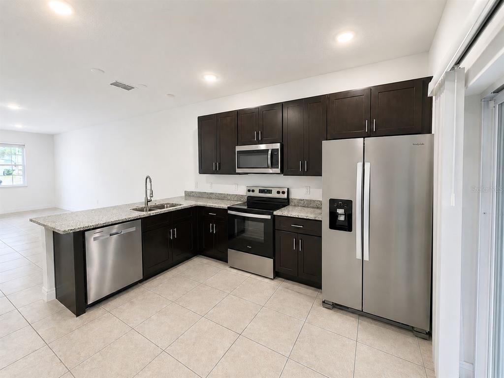A kitchen with dark wood cabinets, granite countertops, and stainless steel appliances — 9130 N MENDOZA WAY UNIT 1, CITRUS SPRINGS, FL
