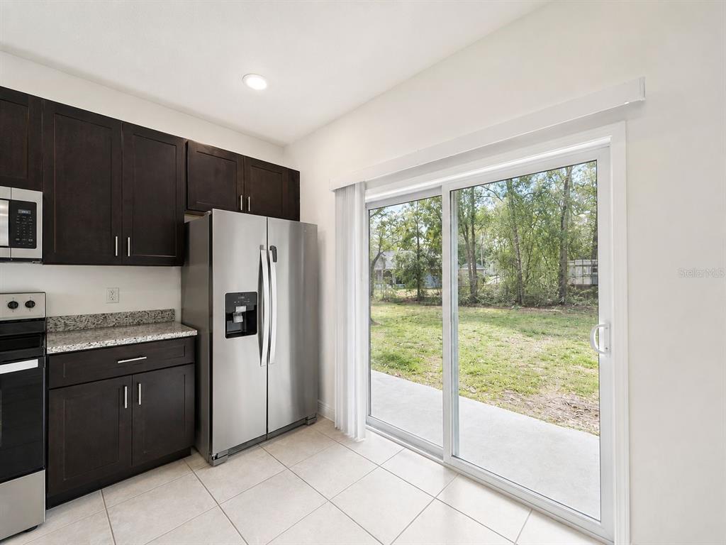 A kitchen with dark cabinets, stainless steel appliances, and a sliding glass door to a yard — 9130 N MENDOZA WAY UNIT 1, CITRUS SPRINGS, FL
