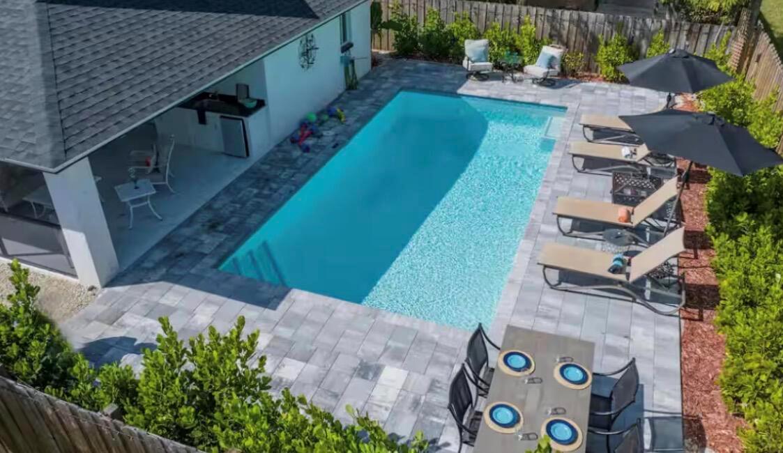 An aerial view of a backyard featuring a rectangular swimming pool, patio, and lounge chairs — 705 N 103rd Ave Avenue N, Naples FL 34108, NAPLES, FL