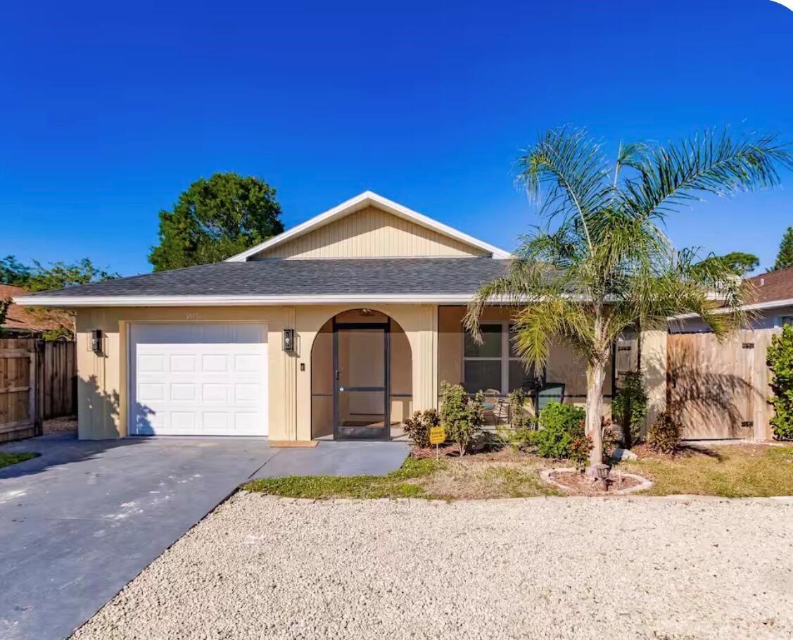 A single-story house with a beige exterior, a garage, and a palm tree in front — 705 N 103rd Ave Avenue N, Naples FL 34108, NAPLES, FL