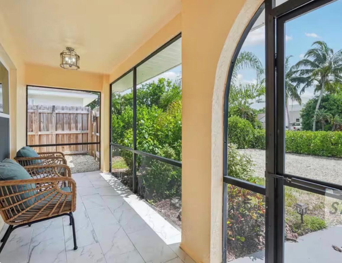 A screened-in porch features tiled flooring, wicker chairs, and views of a landscaped yard — 705 N 103rd Ave Avenue N, Naples FL 34108, NAPLES, FL