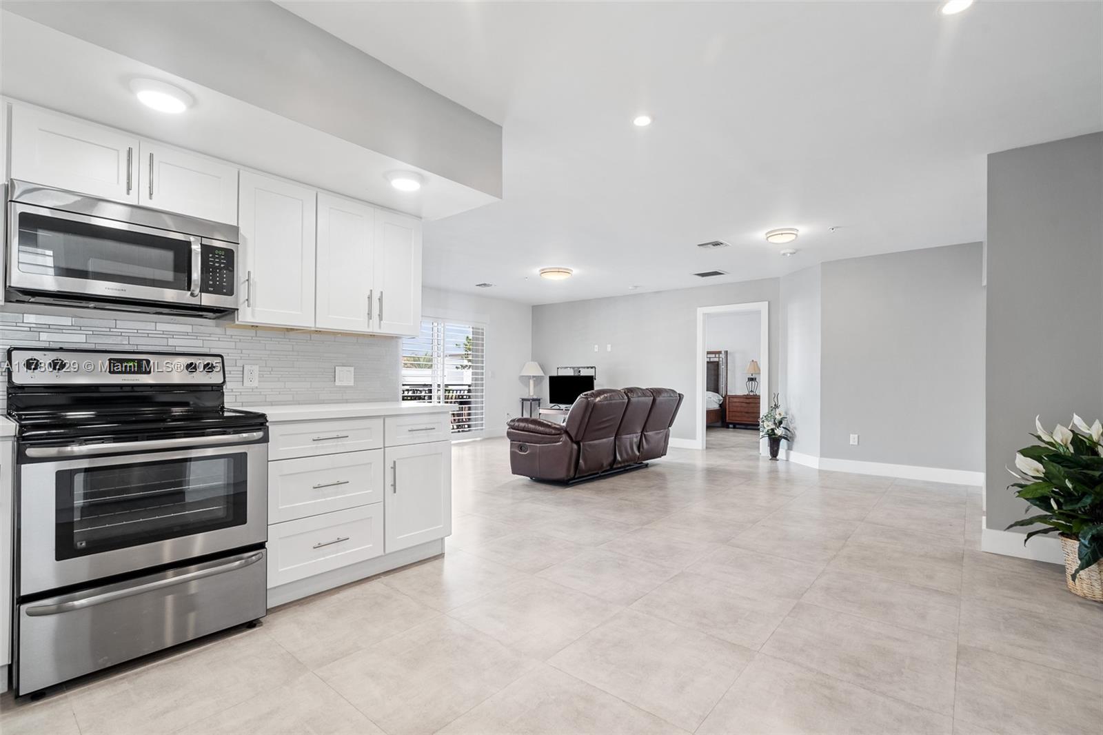 A kitchen with white cabinets and stainless steel appliances opens into a spacious living area — 555 E Dania Beach Blvd # 4, Dania Beach FL 33004, DANIA BEACH, FL