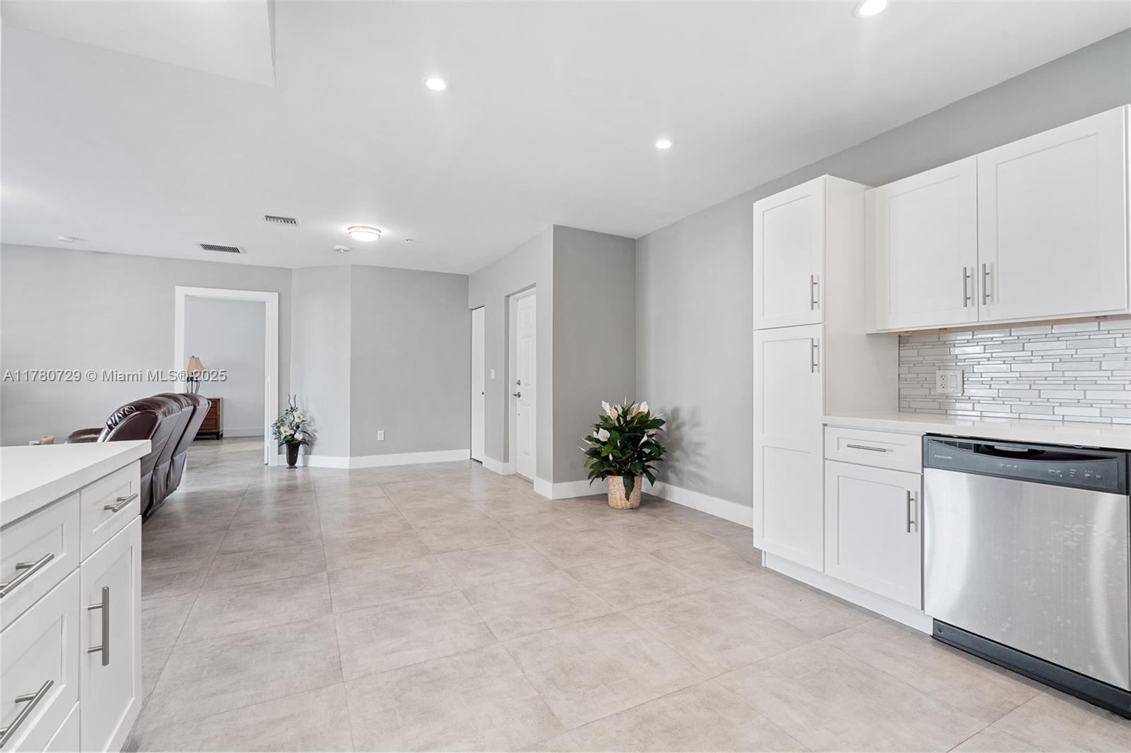 A kitchen with white cabinets and stainless steel appliances opens into a living area — 555 E Dania Beach Blvd # 4, Dania Beach FL 33004, DANIA BEACH, FL