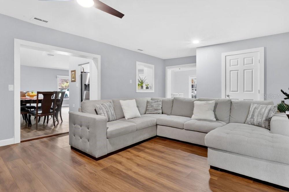 A living room with light gray walls, wood-look flooring, and a large gray sectional sofa — 1092 W RIVIERA BOULEVARD, OVIEDO, FL
