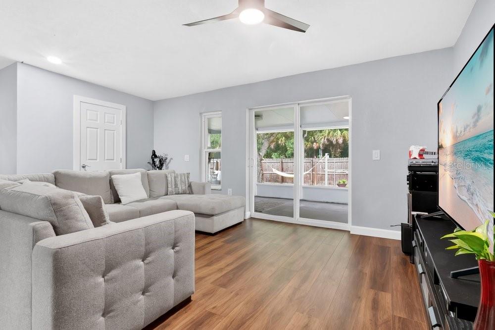 A living room features gray walls, wood-look flooring, a sectional sofa, and a sliding glass door — 1092 W RIVIERA BOULEVARD, OVIEDO, FL