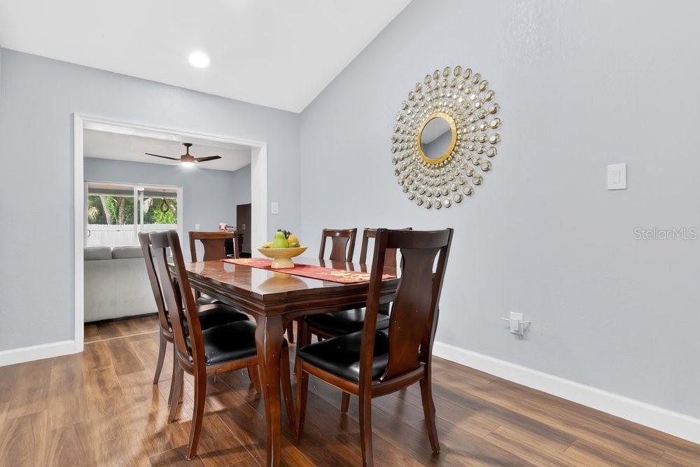 A dining room features a wooden table, dark chairs, and a decorative sunburst wall mirror — 1092 W RIVIERA BOULEVARD, OVIEDO, FL