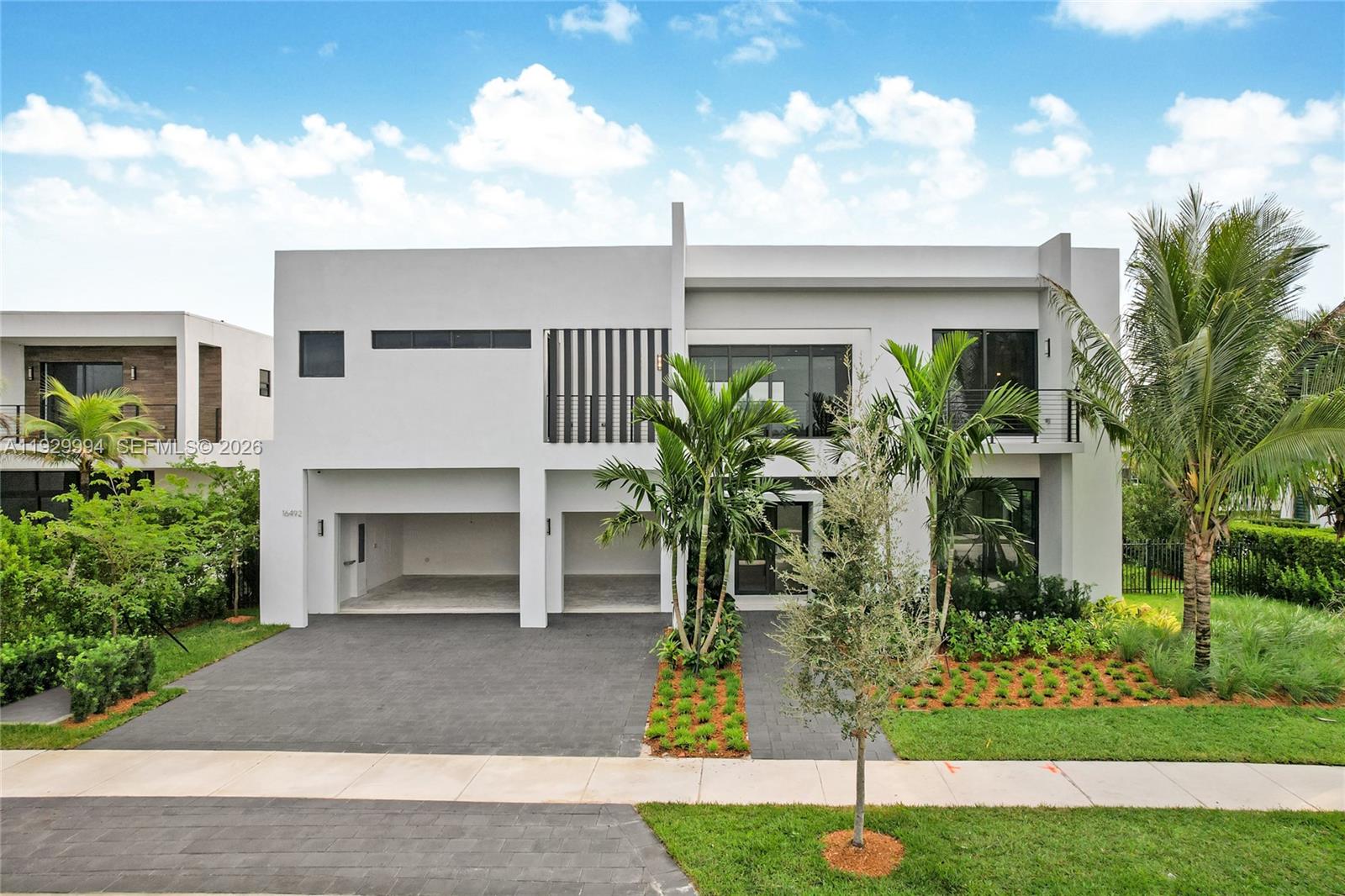 A modern two-story white house features a two-car garage, large windows, and palm tree landscaping — 16492 S Botaniko Dr S, Weston FL 33326, WESTON, FL