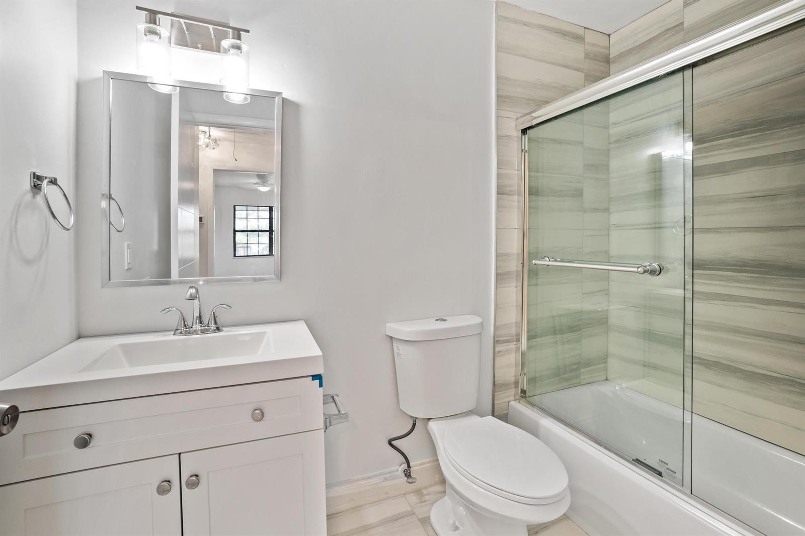 A bathroom features a white vanity, a toilet, and a shower-tub combo with tiled walls — 2355 Linton Ridge Circle # F10, Delray Beach FL 33444, DELRAY BEACH, FL