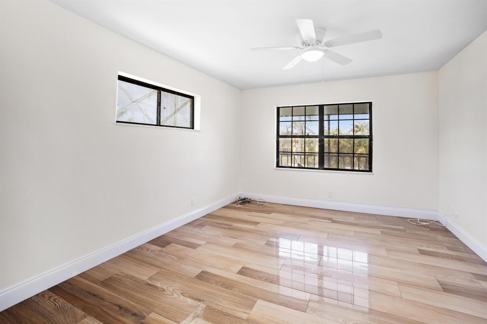 An empty bedroom features white walls, wood-look tile flooring, a ceiling fan, and two windows — 2355 Linton Ridge Circle # F10, Delray Beach FL 33444, DELRAY BEACH, FL