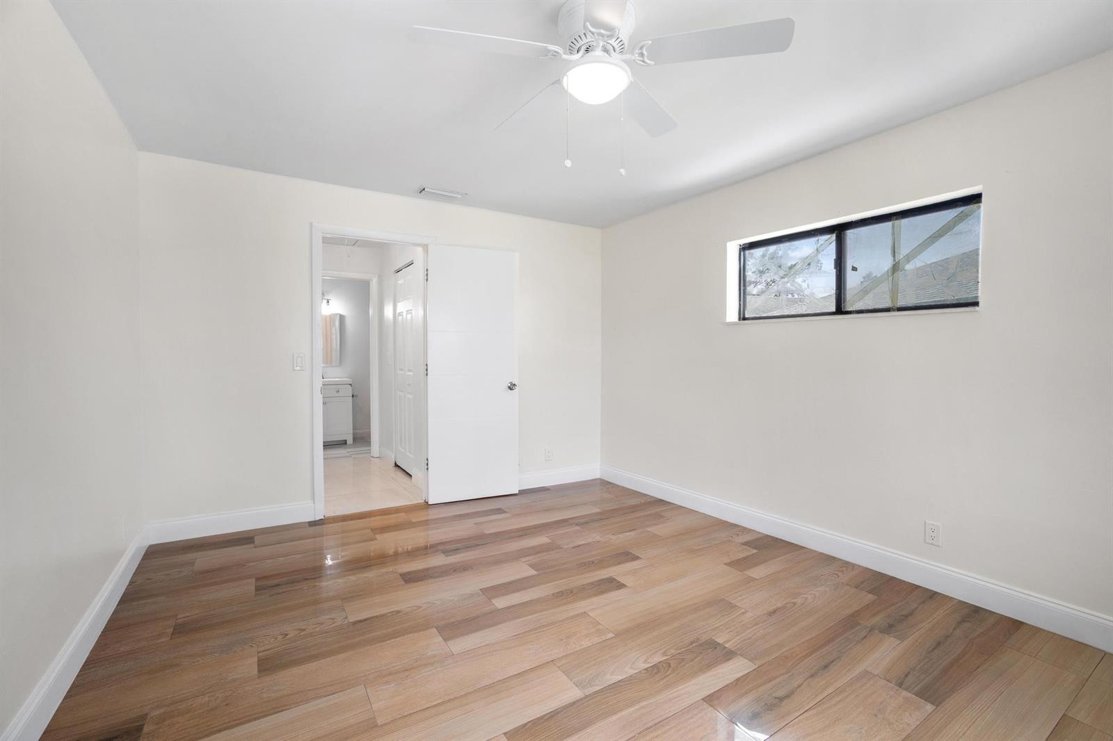 An empty bedroom with light-colored walls, wood-look tile flooring, a ceiling fan, and a window — 2355 Linton Ridge Circle # F10, Delray Beach FL 33444, DELRAY BEACH, FL