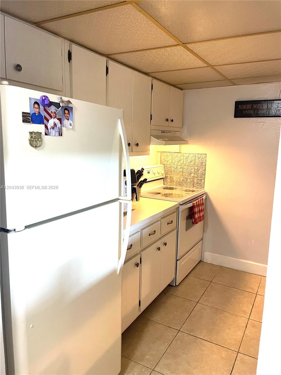A kitchen features white cabinets, a white refrigerator, a stove, and tiled flooring — 7477 SW 82nd St # C318, Miami FL 33143, MIAMI, FL