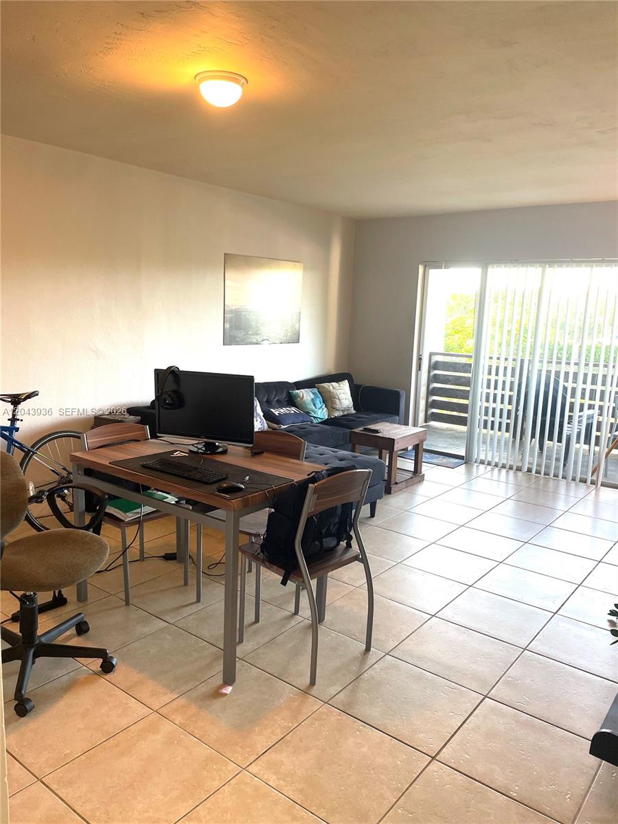 A living room features tile flooring, a desk with a computer, and a sliding glass door — 7477 SW 82nd St # C318, Miami FL 33143, MIAMI, FL