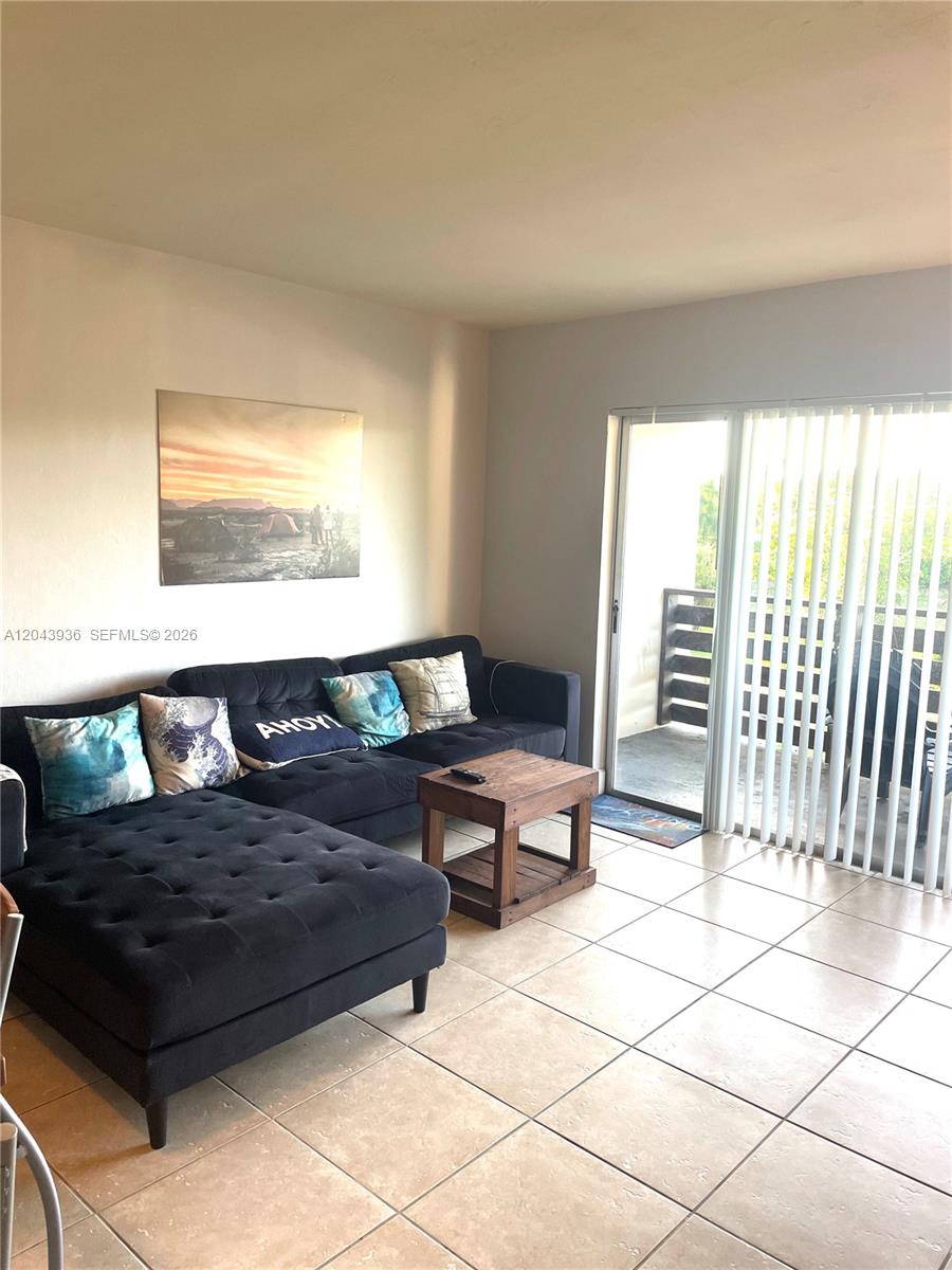 A living room features a black sectional sofa, a wooden coffee table, and tile flooring — 7477 SW 82nd St # C318, Miami FL 33143, MIAMI, FL