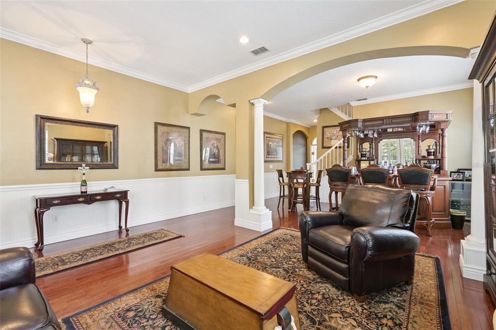 A living room with hardwood floors, a leather armchair, and a built-in wooden bar area — 930 CROTON ROAD, CELEBRATION, FL