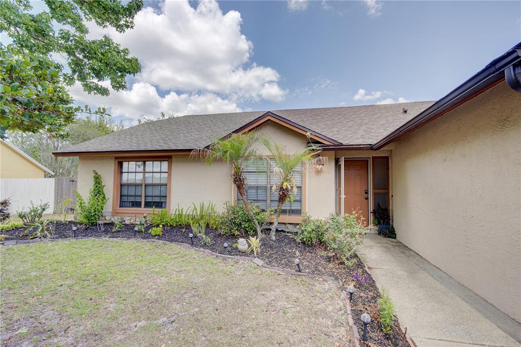 A single-story house with a tan stucco exterior, brown roof, and a front walkway — 1024 DINERO DRIVE, WINTER SPRINGS, FL