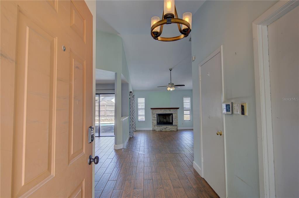 An entryway leads into a living room with a stone fireplace and wood-look tile flooring — 1024 DINERO DRIVE, WINTER SPRINGS, FL