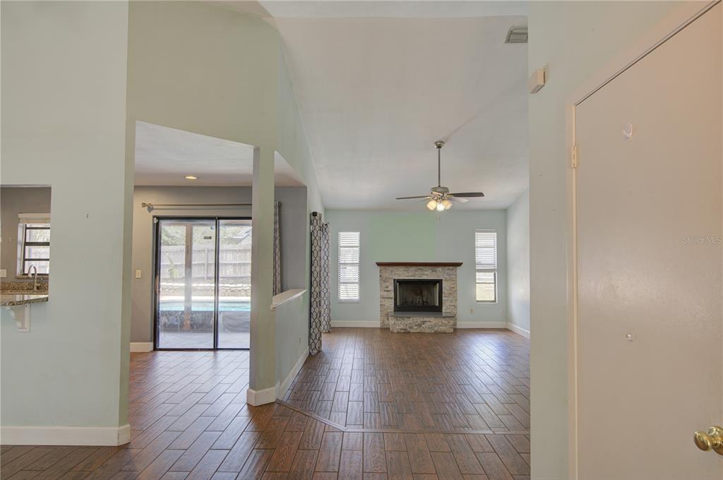A living room with wood-look tile floors, a stone fireplace, and a view into the kitchen — 1024 DINERO DRIVE, WINTER SPRINGS, FL