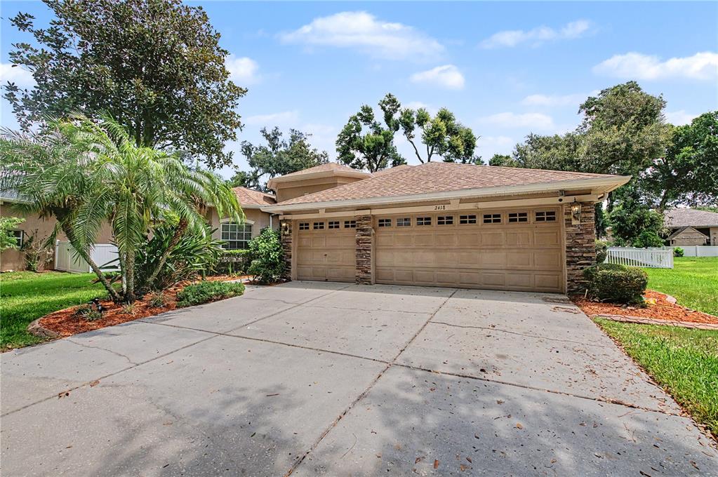 A single-story house with a three-car garage, stone accents, and a concrete driveway — 2418 BLUE STONE COURT, VALRICO, FL