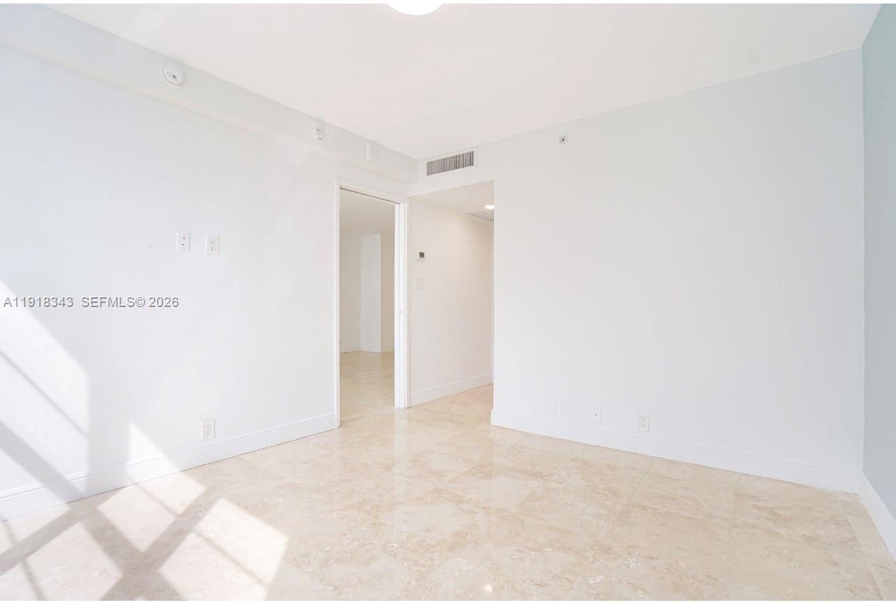 An empty room with white walls, tile flooring, and a doorway leading to another space — 5101 Collins Ave # 14K, Miami Beach FL 33140, MIAMI BEACH, FL