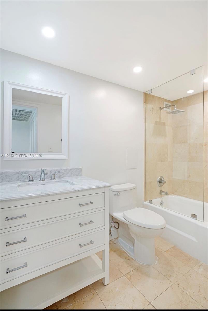 A bathroom features a white vanity with a marble countertop, a toilet, and a bathtub — 5101 Collins Ave # 14K, Miami Beach FL 33140, MIAMI BEACH, FL