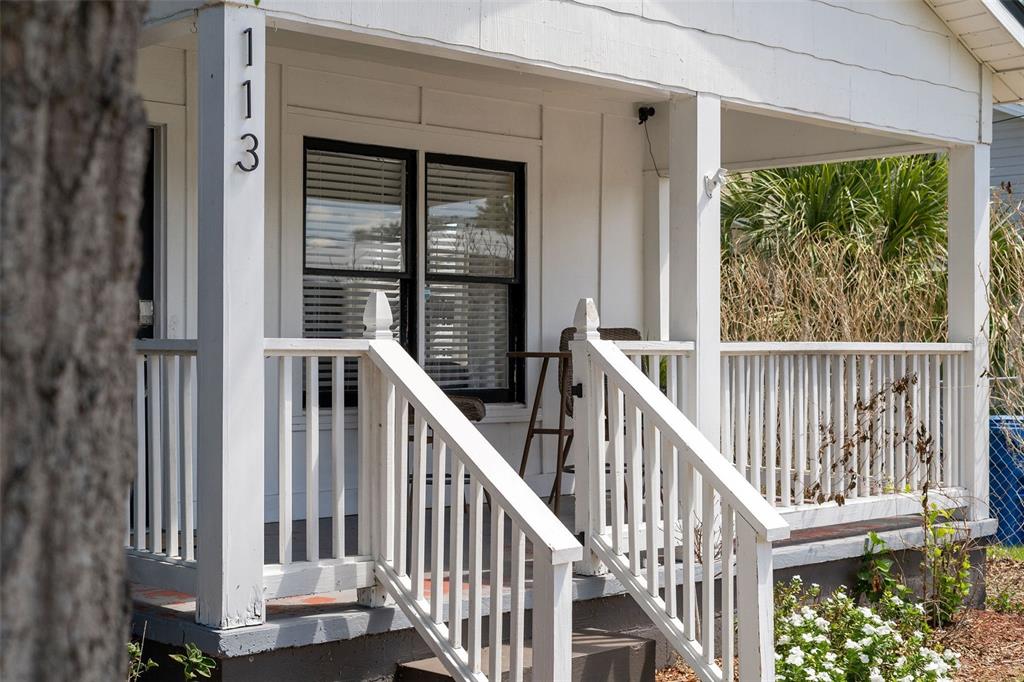A white house with a front porch, wooden railings, and a window with black trim — 113 AVENUE C SE, WINTER HAVEN, FL