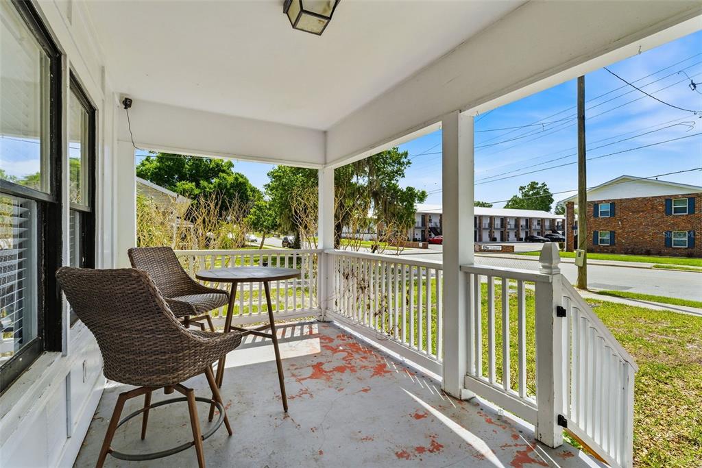 A covered porch features two wicker chairs, a small table, and a white railing — 113 AVENUE C SE, WINTER HAVEN, FL