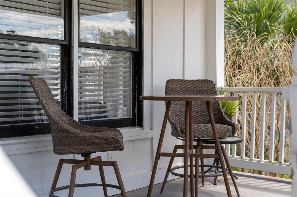 A small outdoor porch features two wicker swivel chairs and a round wooden bistro table — 113 AVENUE C SE, WINTER HAVEN, FL