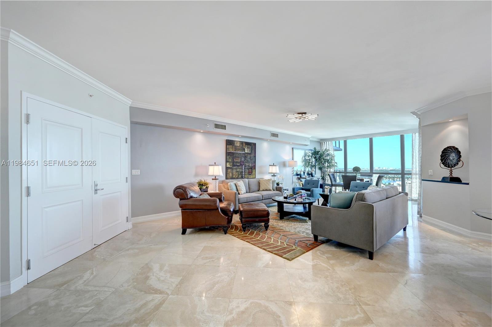 A living room features marble floors, a leather armchair, and a sofa facing floor-to-ceiling windows — 3101 S Ocean Dr # 3203, Hollywood FL 33019, HOLLYWOOD, FL