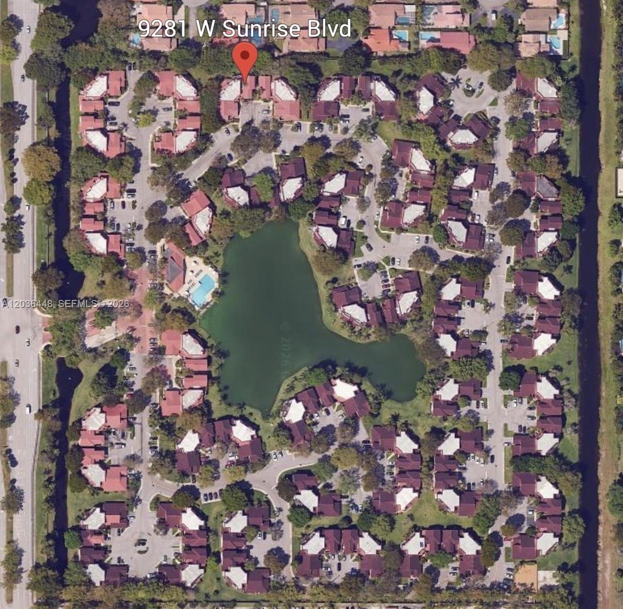An aerial view shows a residential complex with multiple buildings surrounding a central lake — 9281 W Sunrise Blvd, Plantation FL 33322, PLANTATION, FL