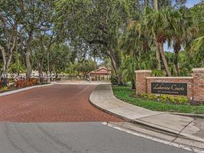 A brick entrance sign for Lakeview Courts at Jacaranda sits beside a paved road and trees — 9281 W Sunrise Blvd, Plantation FL 33322, PLANTATION, FL