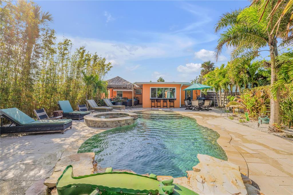 A backyard swimming pool with a hot tub, patio furniture, and tropical landscaping — 308 NORMANDY AVENUE, NEW SMYRNA BEACH, FL