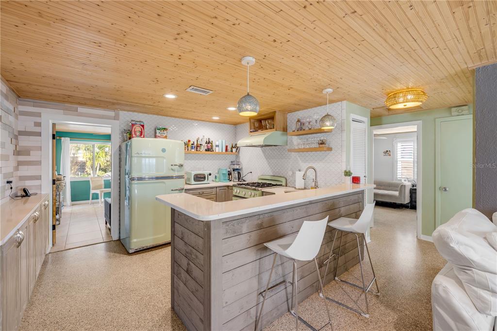 A kitchen features a light green retro refrigerator, a wood-paneled ceiling, and a breakfast bar — 308 NORMANDY AVENUE, NEW SMYRNA BEACH, FL