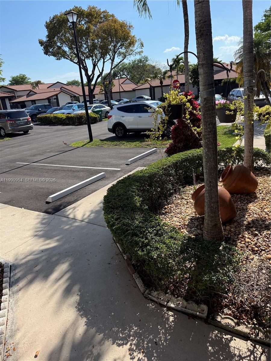 A parking lot with several cars sits adjacent to a landscaped area with palm trees — 4825 SW 149th Ct # 18B, Miami FL 33185, MIAMI, FL
