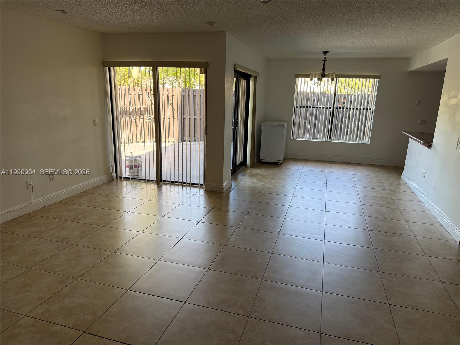 An open-concept living and dining area features beige tile flooring and sliding glass patio doors — 4825 SW 149th Ct # 18B, Miami FL 33185, MIAMI, FL