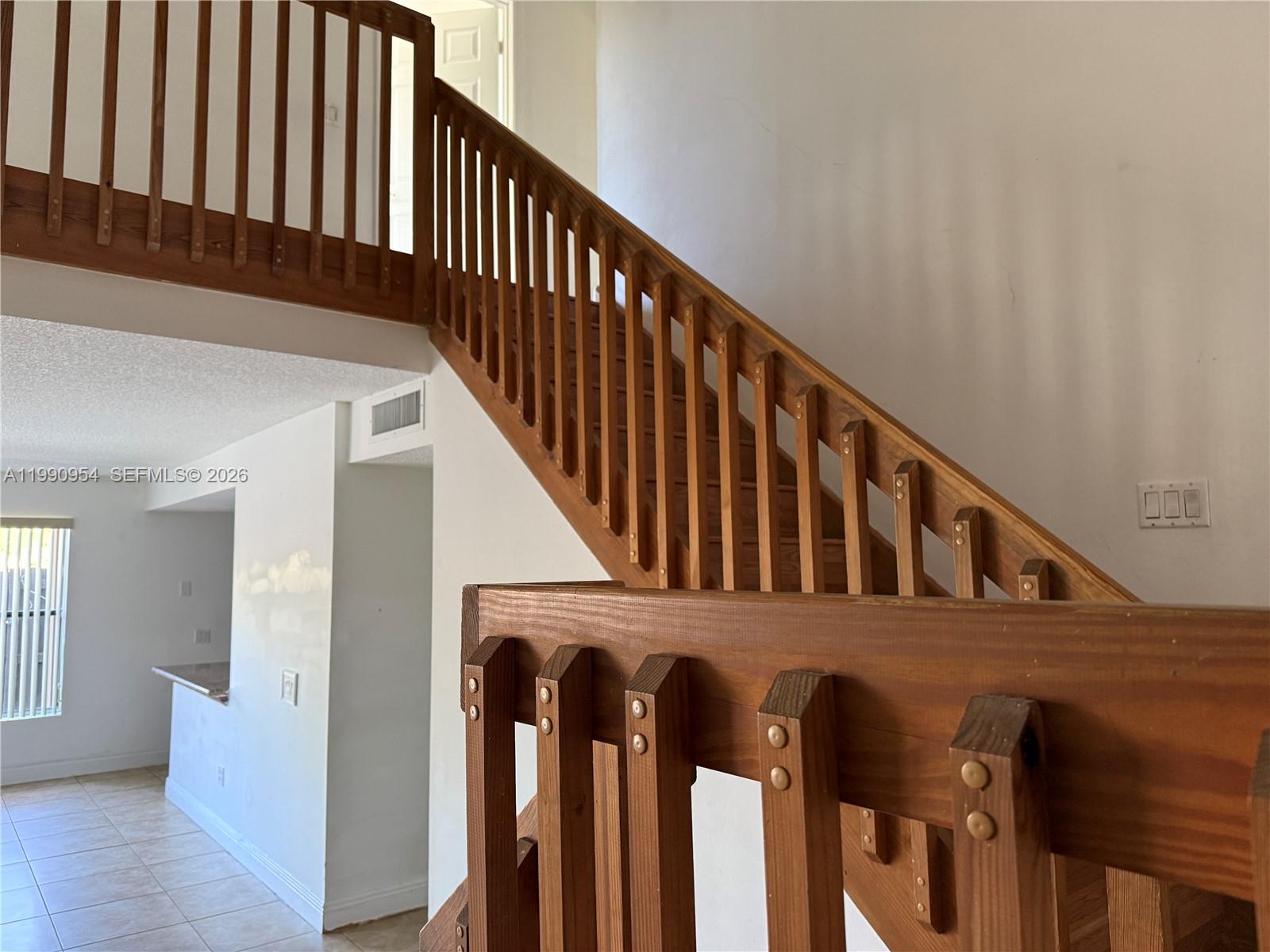 A wooden staircase with a railing leads to an upper level in a home interior — 4825 SW 149th Ct # 18B, Miami FL 33185, MIAMI, FL