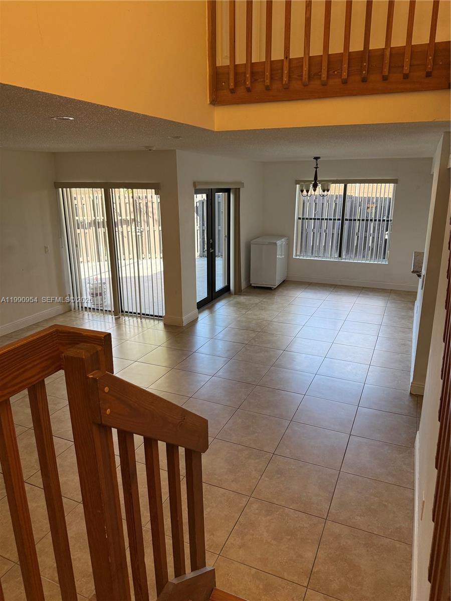 A view from a staircase looking down into a tiled living area with sliding doors — 4825 SW 149th Ct # 18B, Miami FL 33185, MIAMI, FL