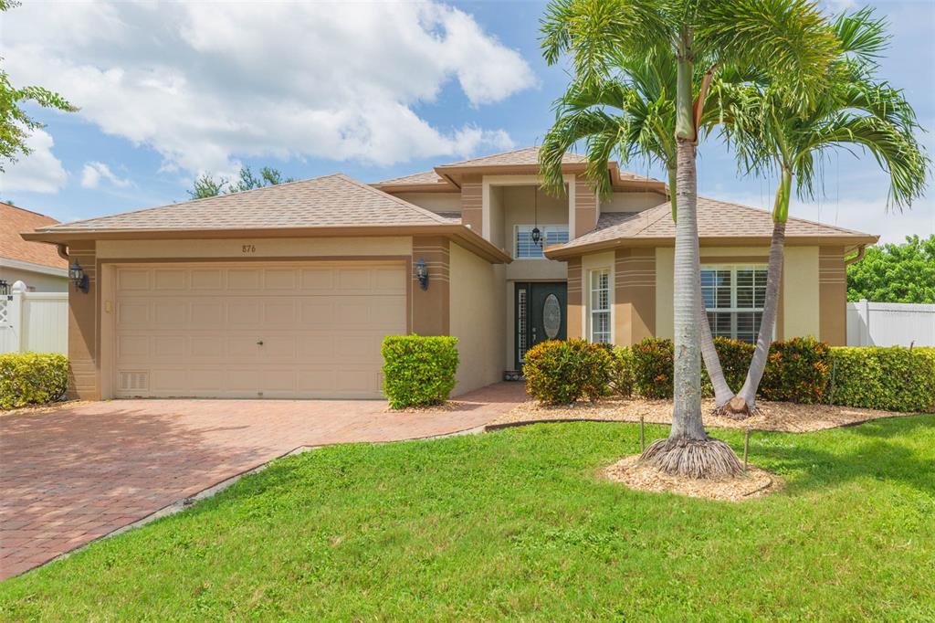 A single-story suburban house with a tan stucco exterior, a two-car garage, and palm trees — 876 ADDISON DRIVE NE, ST PETERSBURG, FL
