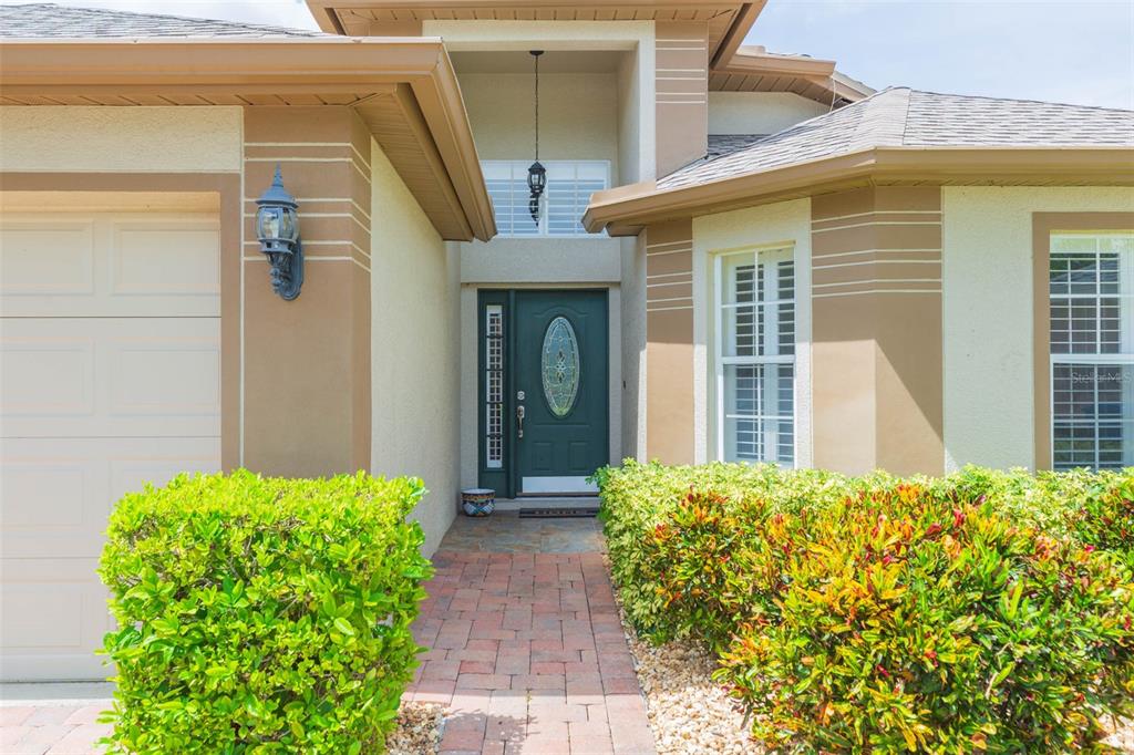 A front exterior view of a house featuring a green door and brick walkway — 876 ADDISON DRIVE NE, ST PETERSBURG, FL