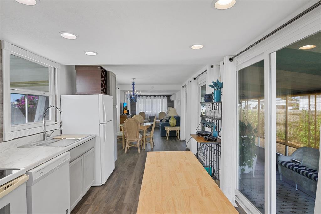 A kitchen with a wooden island, white appliances, and gray cabinets opens into a dining area — 2010 KEPNER DRIVE, HOLIDAY, FL