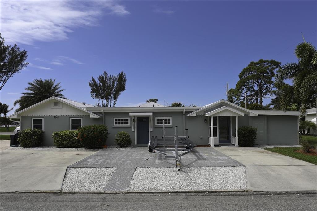 A single-story gray house features a paved driveway, a boat trailer, and two entrance doors — 4621 103RD STREET W UNIT B, BRADENTON, FL