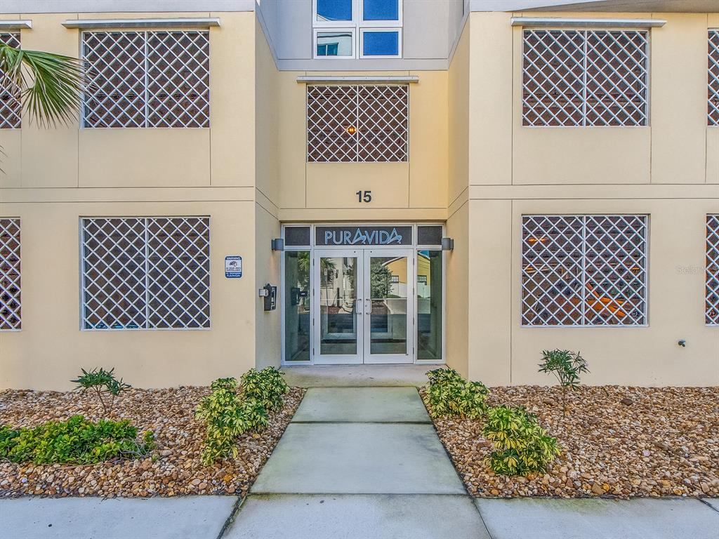 The exterior of a multi-story building features a glass entrance door labeled Puravida — 15 AVALON STREET UNIT 403, CLEARWATER BEACH, FL