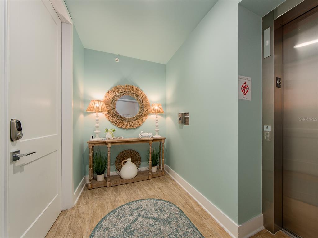 A hallway features light blue walls, a wooden console table, a mirror, and an elevator — 15 AVALON STREET UNIT 403, CLEARWATER BEACH, FL