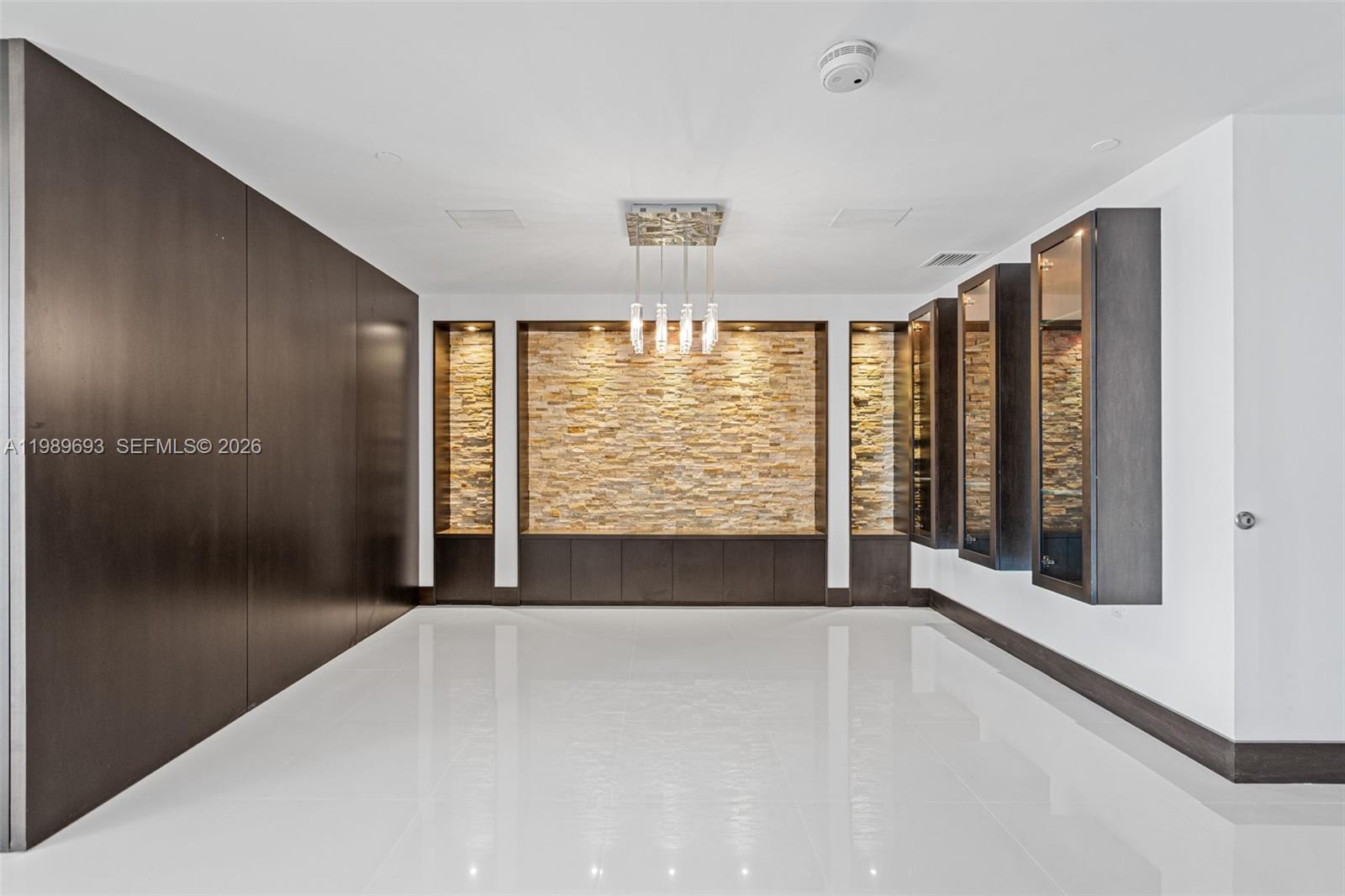 A modern room features white tile floors, dark wood paneling, and a stone accent wall — 200 Biscayne Boulevard Way # 3707, Miami FL 33131, MIAMI, FL