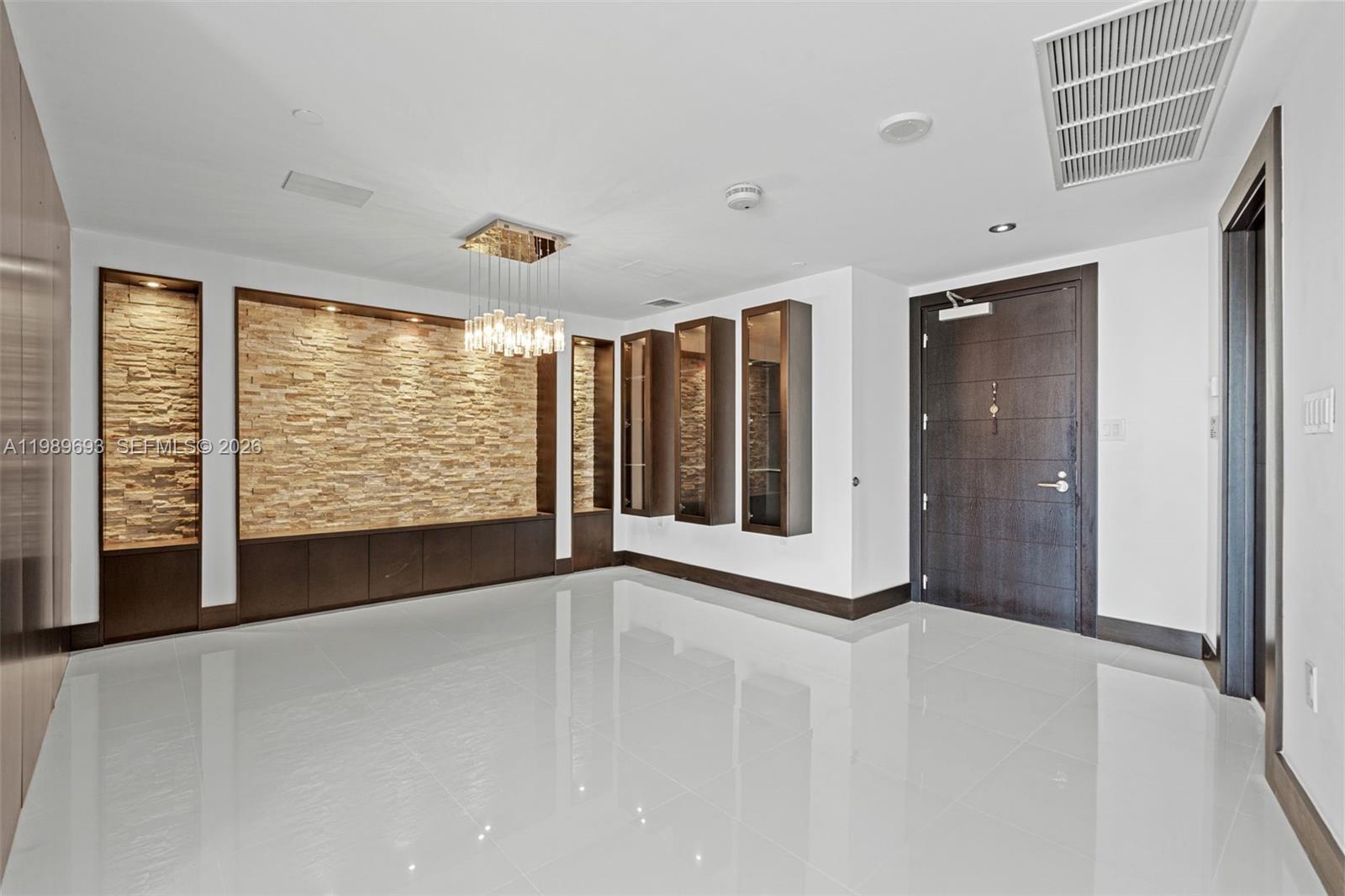A modern room features white tile floors, a stone accent wall, and dark wood cabinetry — 200 Biscayne Boulevard Way # 3707, Miami FL 33131, MIAMI, FL