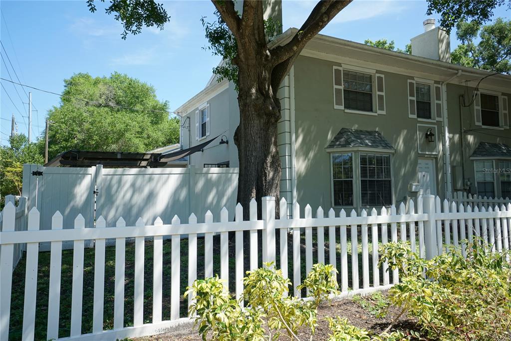 A two-story house with a white picket fence and a large tree in the front yard — 3323 W SWANN AVENUE, TAMPA, FL