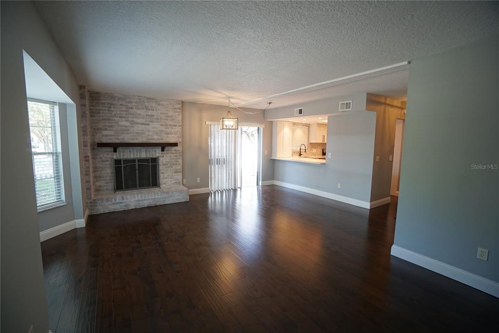 An open-concept living room features dark wood floors, a brick fireplace, and an adjacent kitchen — 3323 W SWANN AVENUE, TAMPA, FL