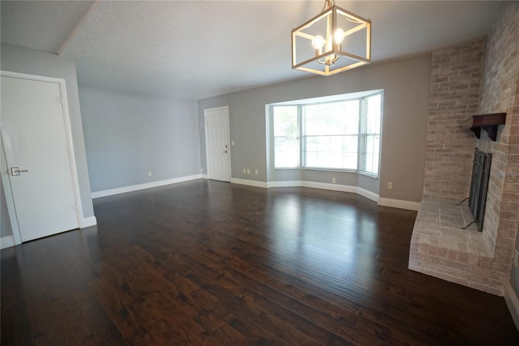 A living room features dark hardwood floors, a brick fireplace, and a bay window — 3323 W SWANN AVENUE, TAMPA, FL