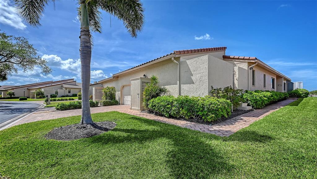 A single-story stucco house features a palm tree, brick walkway, and manicured landscaping — 2339 HARBOUR OAKS DRIVE, LONGBOAT KEY, FL