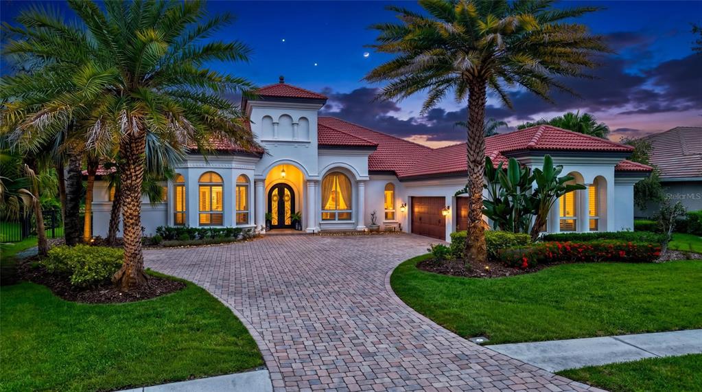 A Mediterranean-style house with a red tile roof and a paver driveway at dusk — 14742 WATERCHASE BOULEVARD, TAMPA, FL